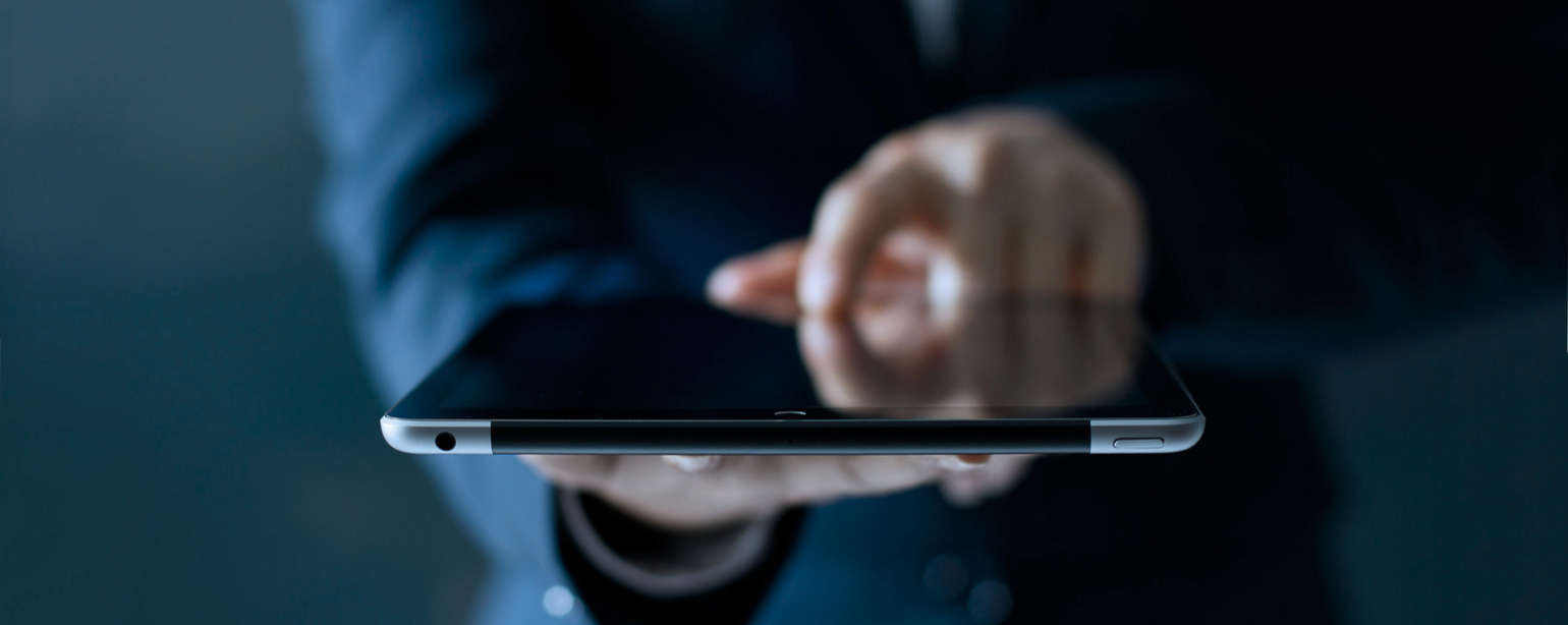 Businessman holding and touching digital tablet computer on dark background