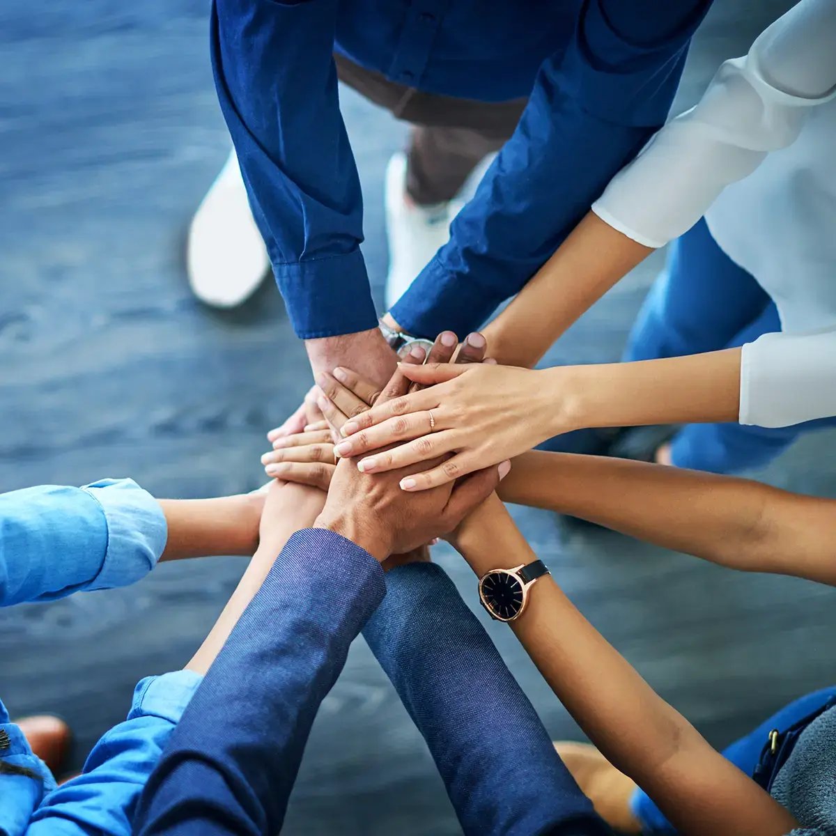Hands stacked together in a circle, showing team unity and cooperation
