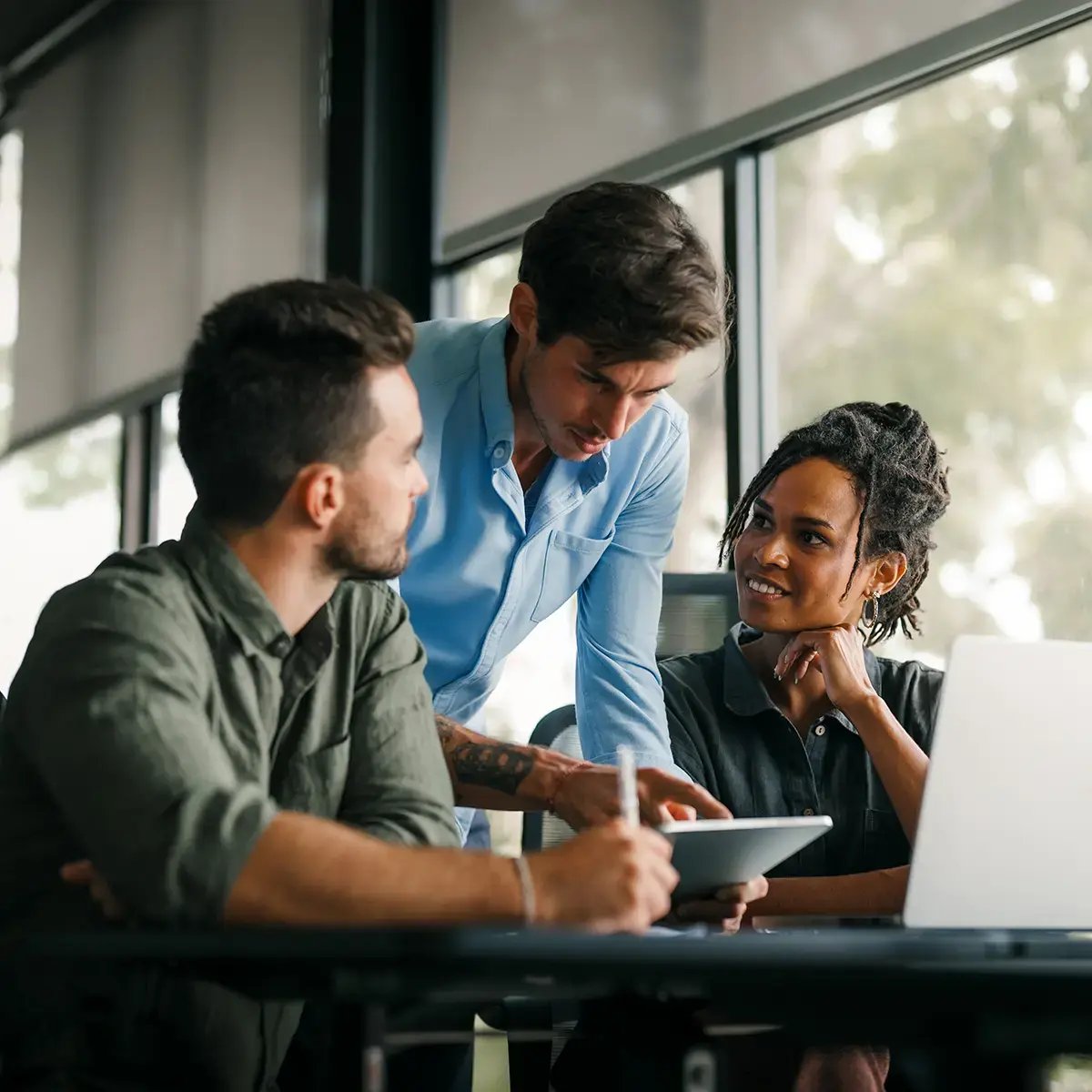 Three people are collaborating in a modern office