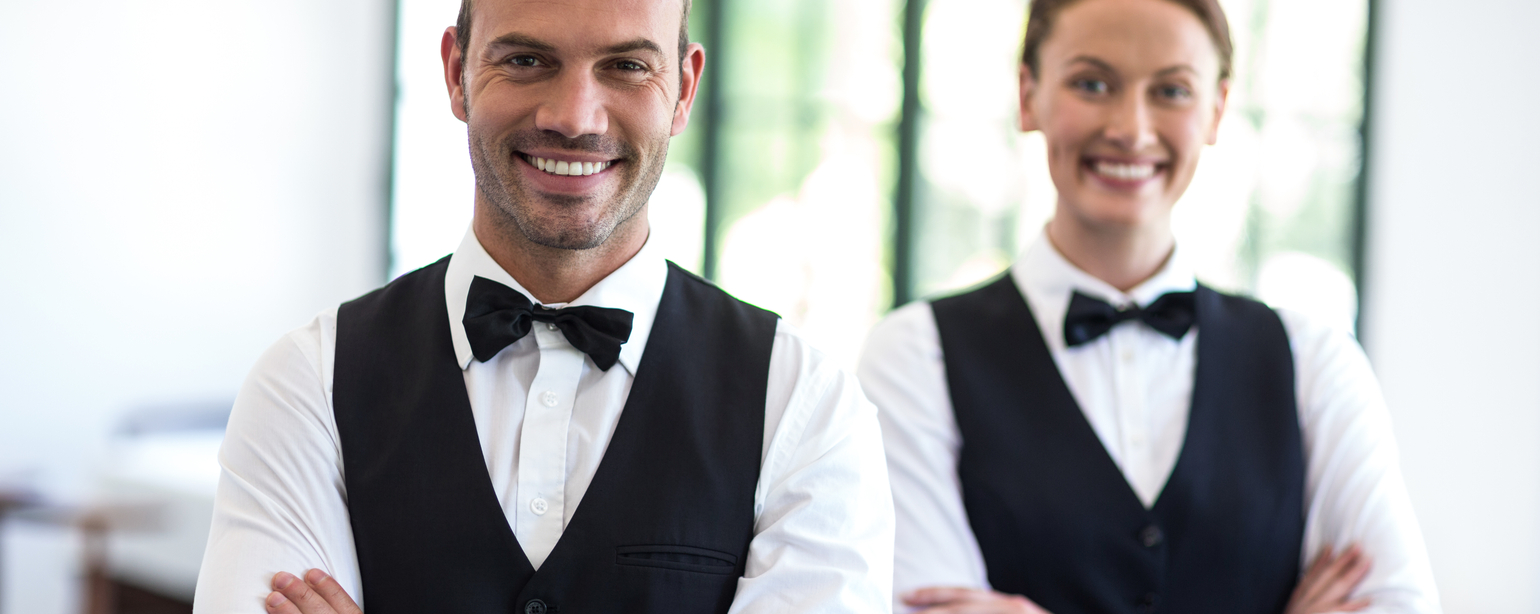 Waiting staff smiling at camera in a commercial kitchen