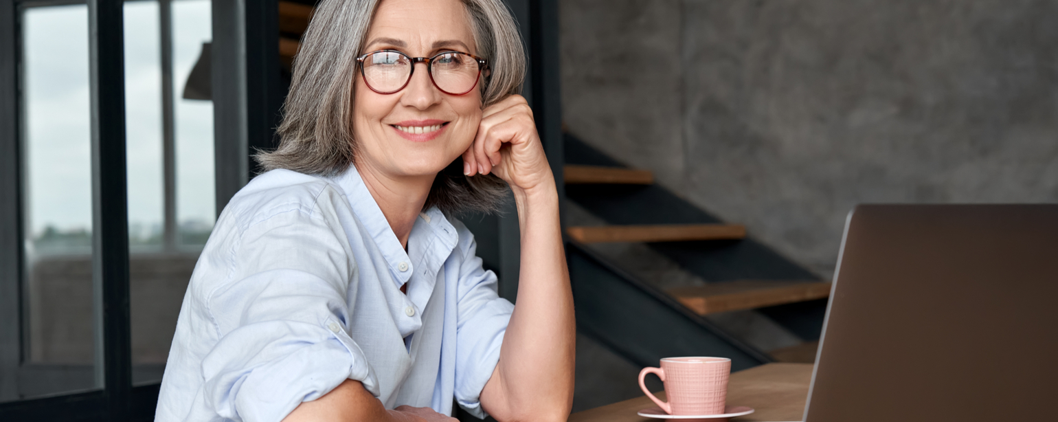 mature gray-haired lady executive looking at camera sitting at table