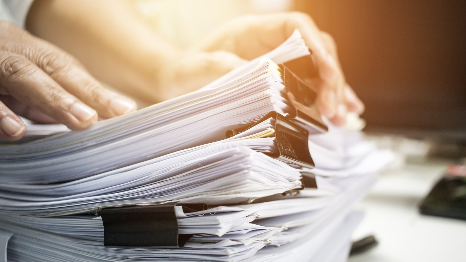 Businessman hands working in Stacks of paper files for searching information on work desk