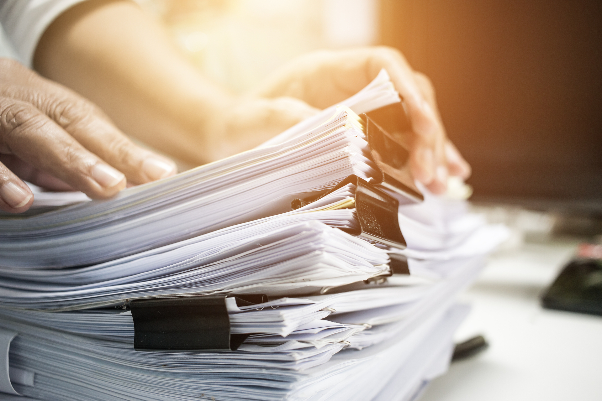 Businessman hands working in Stacks of paper files for searching information on work desk