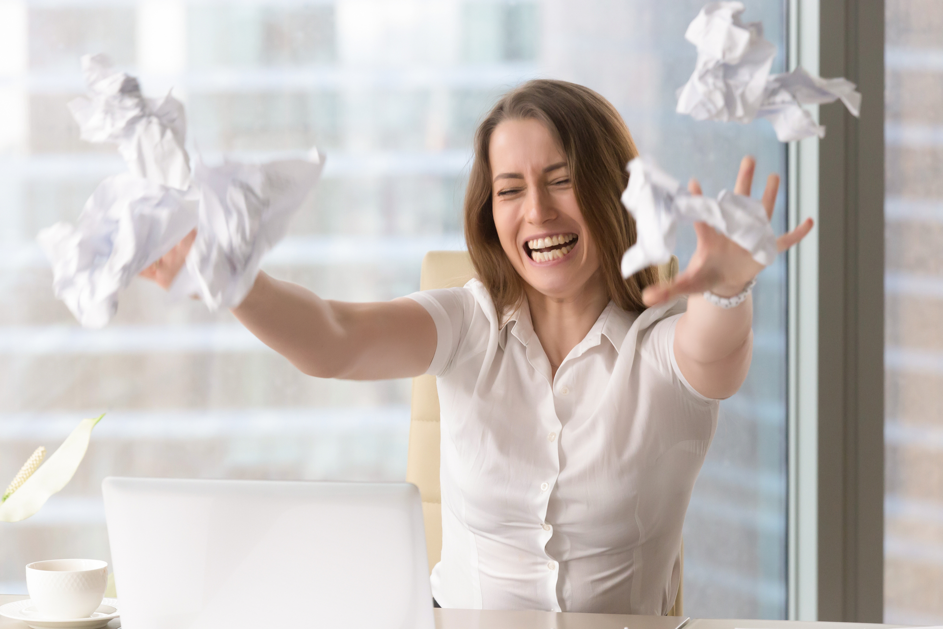 Furious businesswoman with wrathful face expression throwing crumbled papers