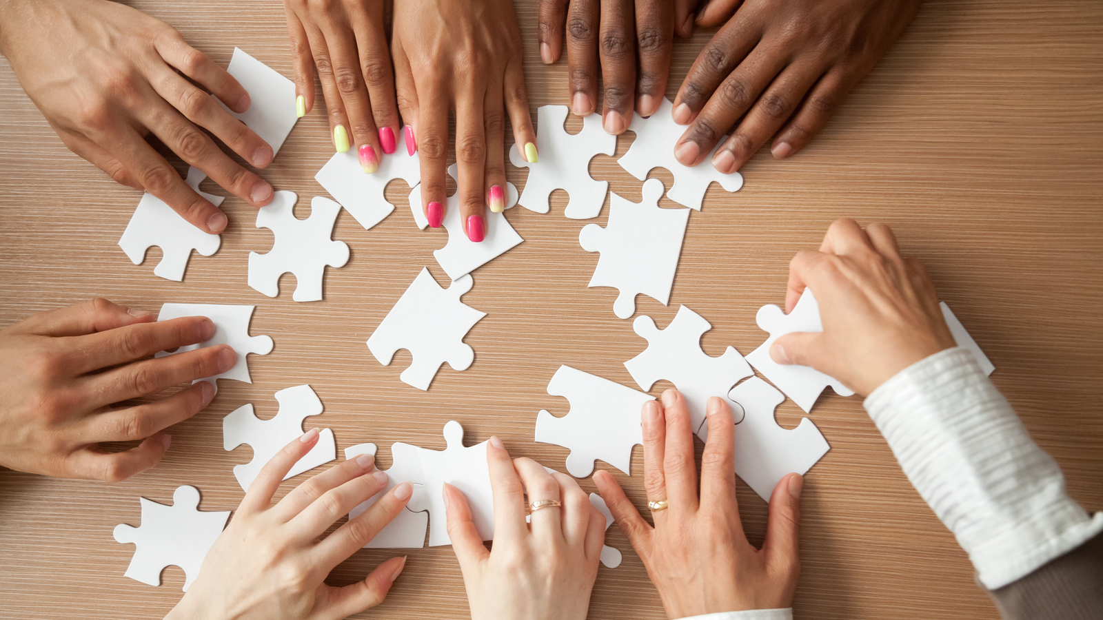 Hands of diverse people assembling jigsaw puzzle