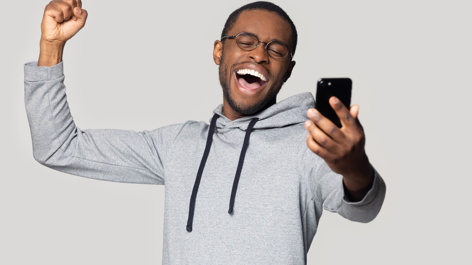 Head shot overjoyed happy millennial black man holding smartphone