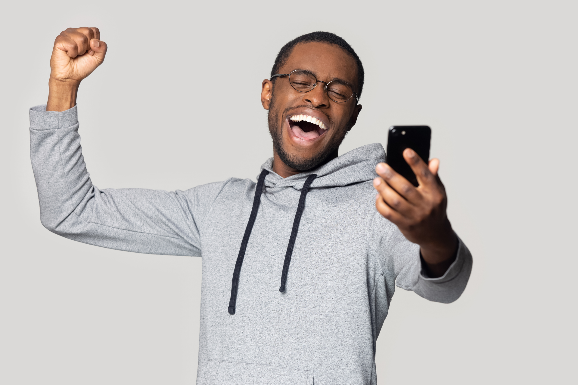 Head shot overjoyed happy millennial black man holding smartphone