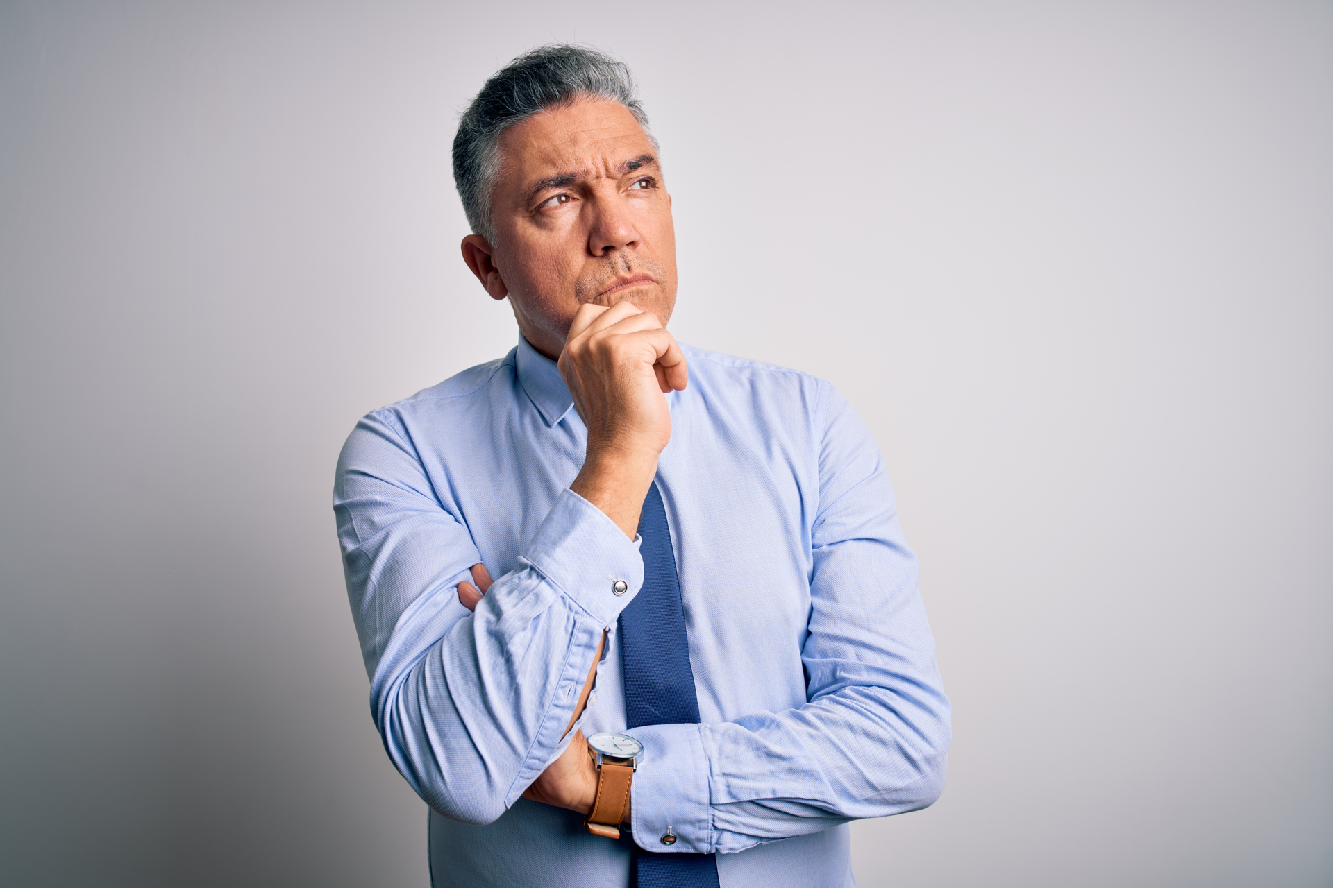 Middle age grey-haired business man wearing elegant shirt and tie with hand on chin thinking about question