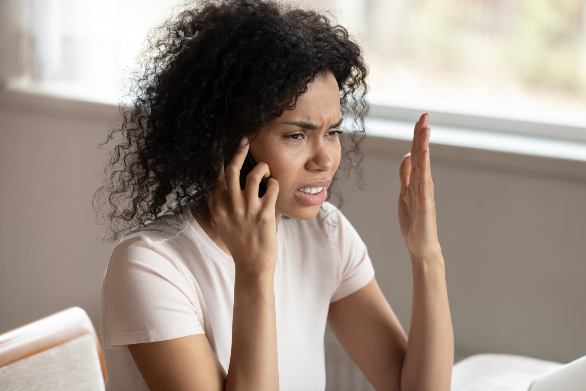 Unhappy black woman talking on smartphone