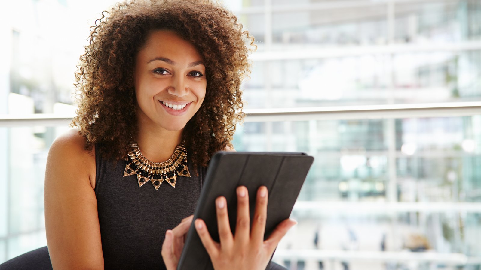 Young businesswoman using tablet computer in modern interior feature