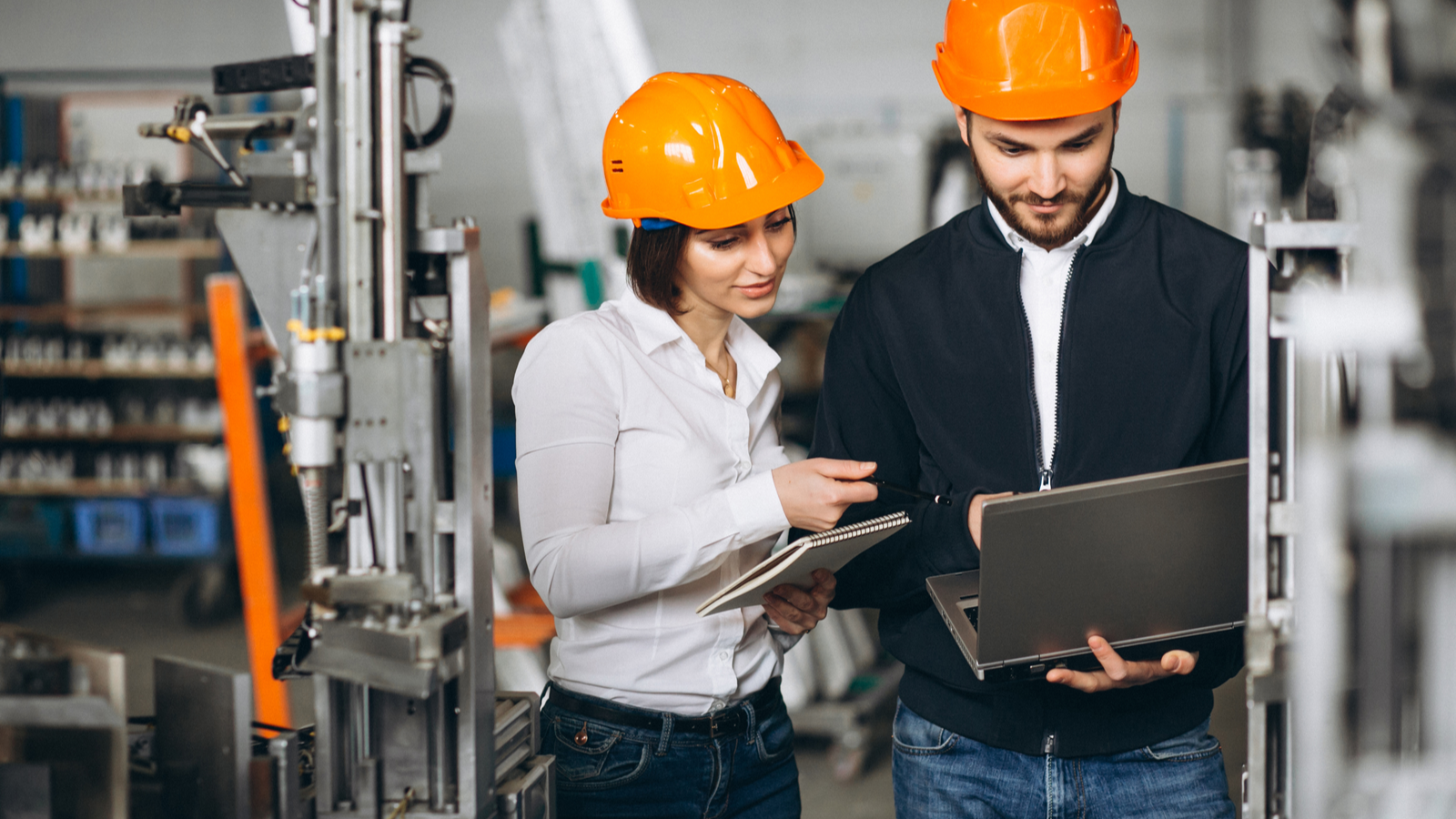 Female and male maintanence workers discussing CMMS software on laptop