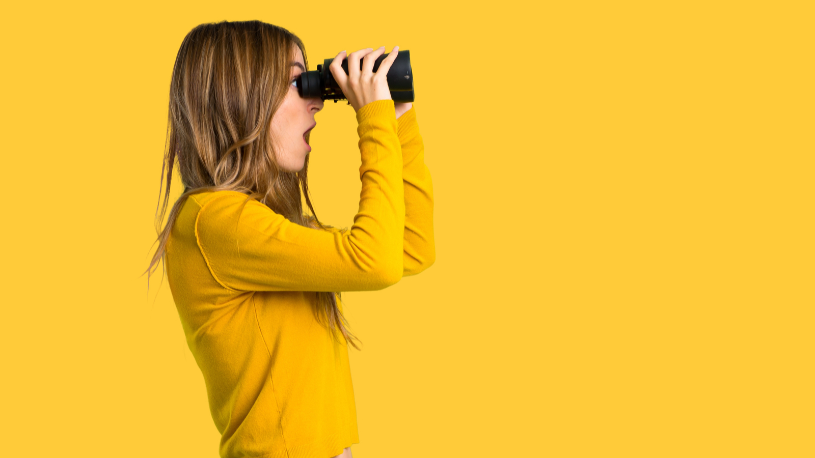 woman with yellow sweater and looking in the distance with binoculars